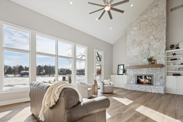 living room with ceiling fan, high vaulted ceiling, light hardwood / wood-style flooring, and a fireplace