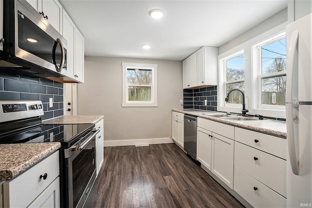 kitchen featuring white cabinets, dark wood-type flooring, stainless steel appliances, sink, and backsplash