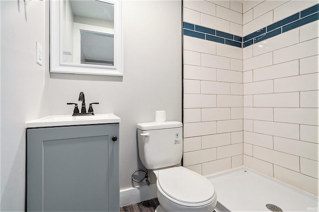 bathroom with toilet, vanity, and a tile shower