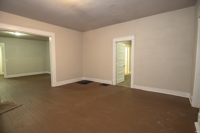 empty room with dark hardwood / wood-style floors and a textured ceiling