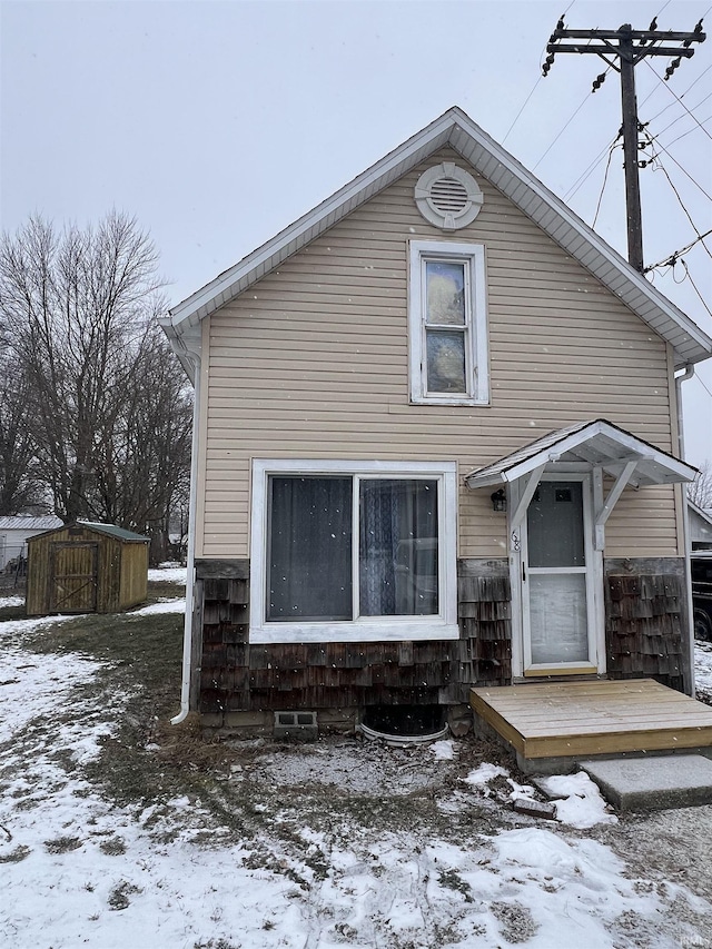 snow covered back of property with a storage unit