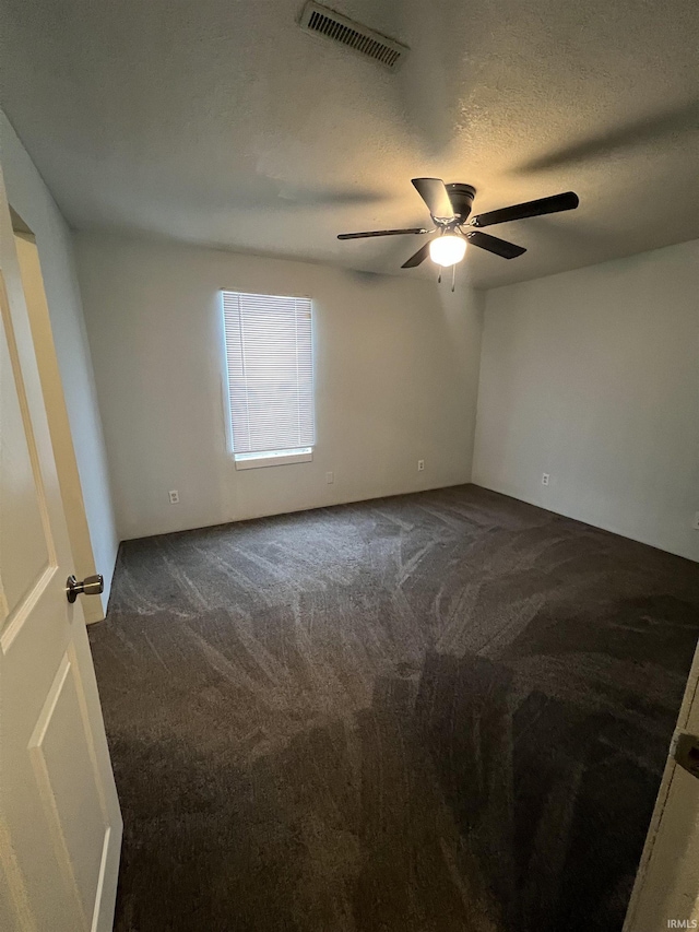 carpeted spare room featuring ceiling fan and a textured ceiling