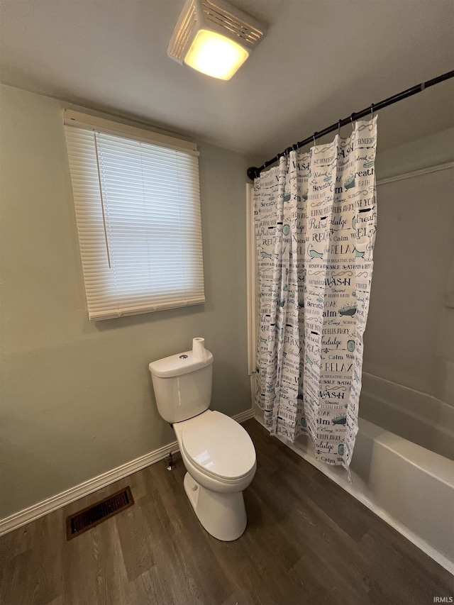 bathroom with hardwood / wood-style floors, toilet, and shower / bath combination with curtain