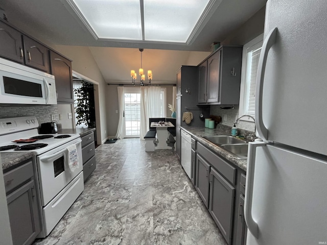 kitchen featuring vaulted ceiling, sink, decorative light fixtures, tasteful backsplash, and white appliances