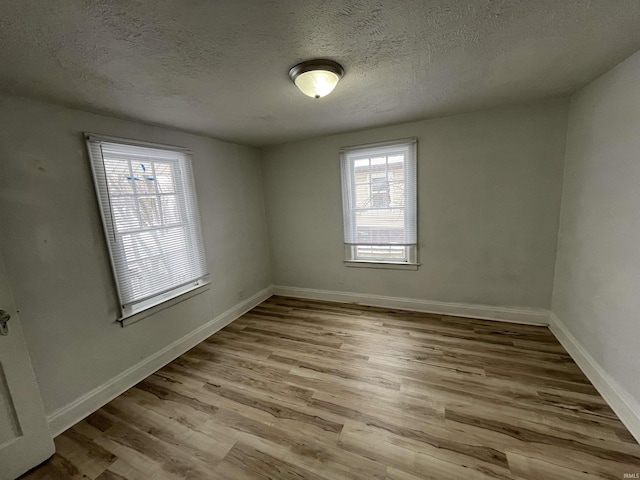 empty room with light hardwood / wood-style floors and a textured ceiling