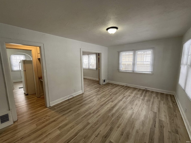 empty room featuring light wood-type flooring and a textured ceiling