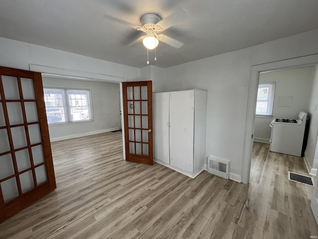 unfurnished bedroom with multiple windows, light hardwood / wood-style floors, ceiling fan, and washer / dryer