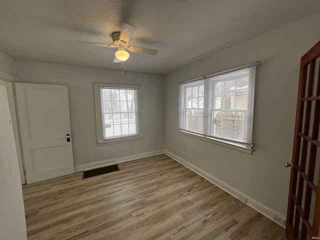 spare room with ceiling fan, a textured ceiling, and light hardwood / wood-style flooring