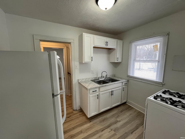 kitchen with sink, white appliances, a textured ceiling, and white cabinets