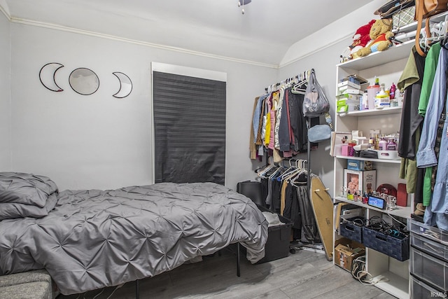 bedroom with lofted ceiling, crown molding, and light wood-type flooring