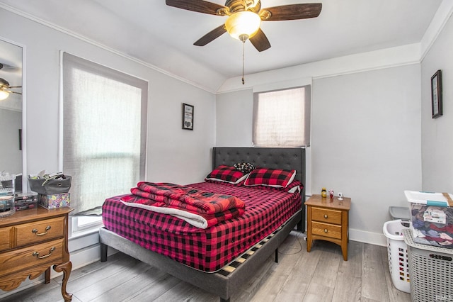 bedroom featuring ceiling fan, multiple windows, hardwood / wood-style flooring, and vaulted ceiling