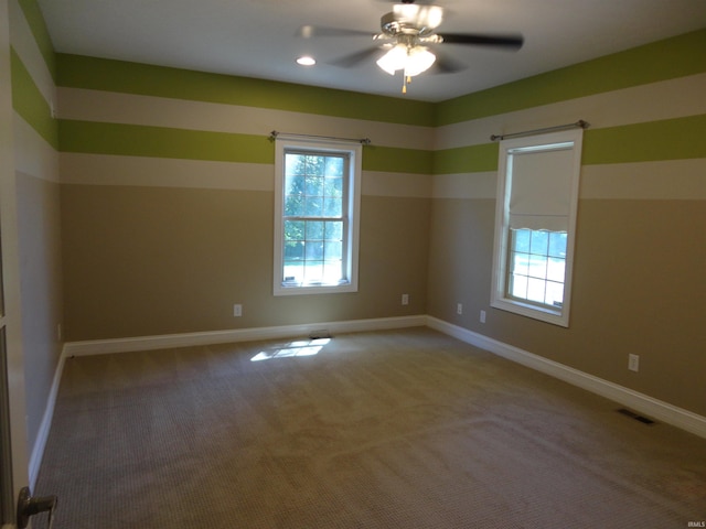 carpeted spare room featuring ceiling fan and a wealth of natural light