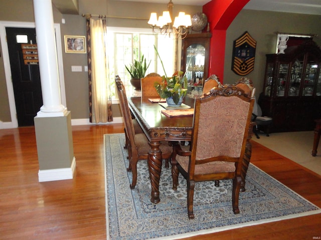 dining area featuring decorative columns, hardwood / wood-style flooring, and an inviting chandelier