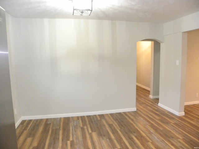 unfurnished room featuring a textured ceiling and dark hardwood / wood-style flooring