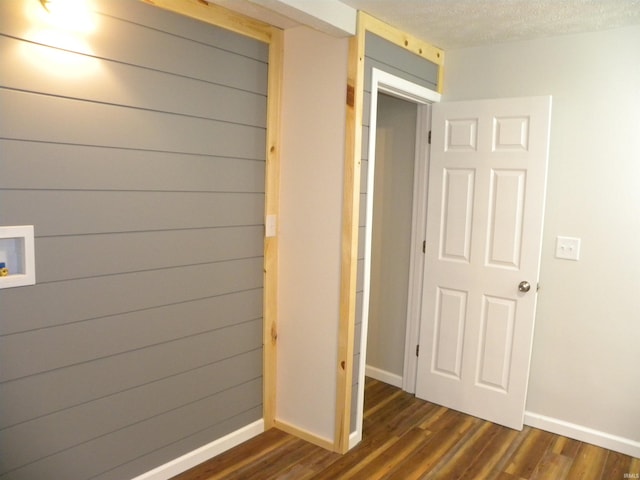 hall with wood walls, dark hardwood / wood-style floors, and a textured ceiling