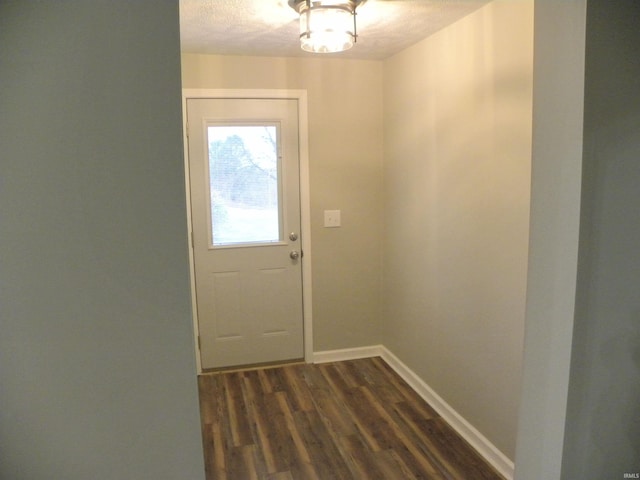 doorway to outside with dark wood-type flooring and a textured ceiling