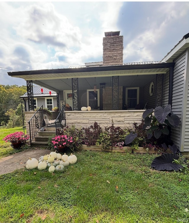 back of house with covered porch and a yard