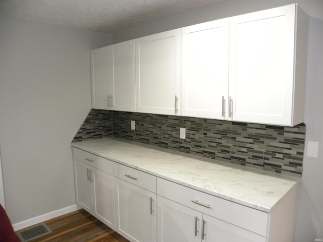 kitchen featuring backsplash, white cabinets, and light stone countertops