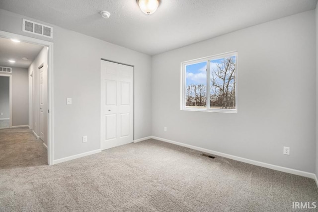 unfurnished bedroom with a textured ceiling, a closet, and carpet flooring