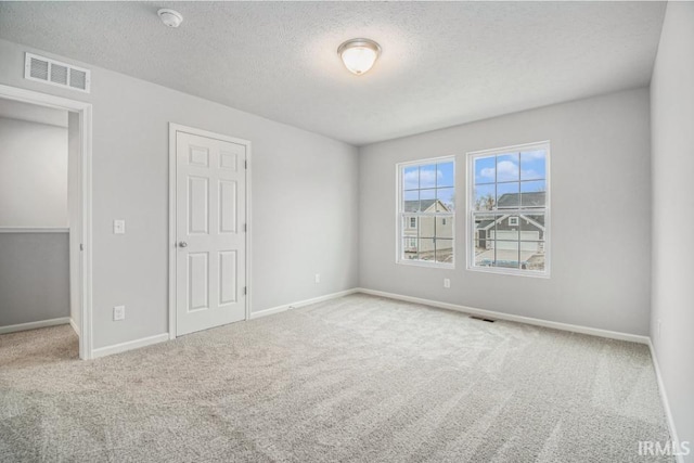 spare room featuring a textured ceiling and carpet