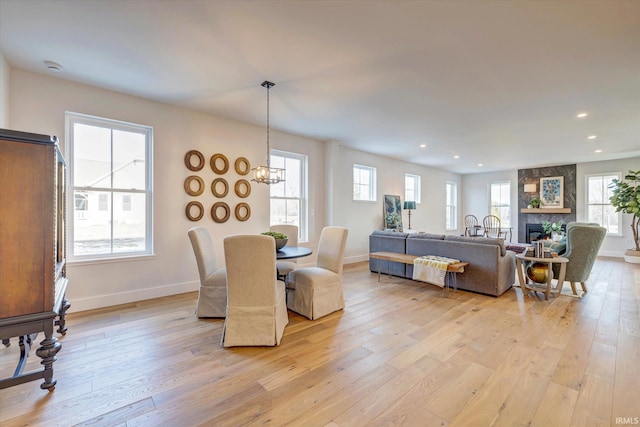 dining space featuring light wood-type flooring, a healthy amount of sunlight, and a fireplace