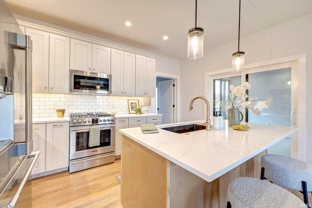 kitchen with decorative light fixtures, sink, white cabinets, and stainless steel appliances