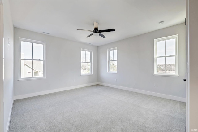 carpeted empty room featuring ceiling fan and plenty of natural light