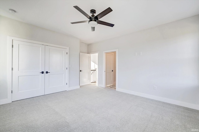 unfurnished bedroom featuring light carpet, a closet, and ceiling fan