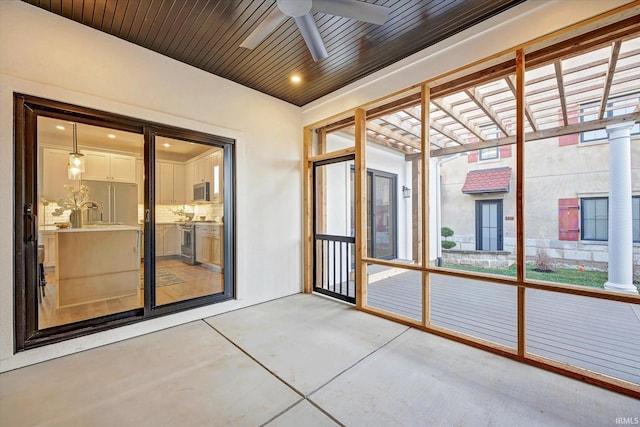 unfurnished sunroom with decorative columns, ceiling fan, and wooden ceiling