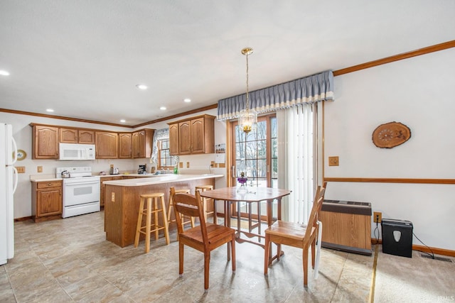 kitchen with decorative light fixtures, white appliances, crown molding, and a breakfast bar