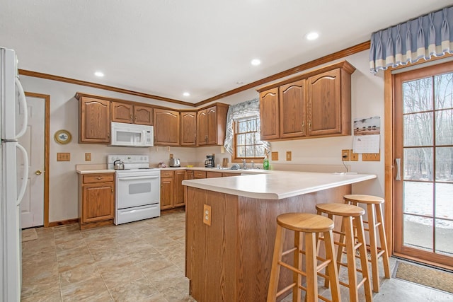 kitchen with white appliances, sink, ornamental molding, kitchen peninsula, and a breakfast bar area