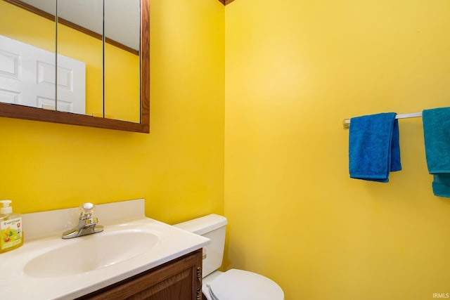 bathroom with toilet, vanity, and crown molding