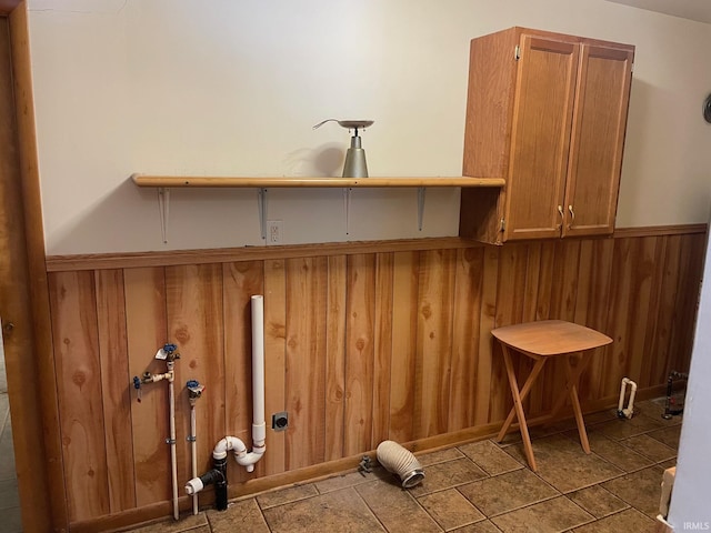 laundry area featuring cabinets and wooden walls