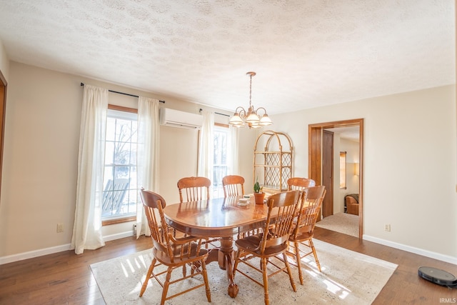 dining space with a chandelier, a wealth of natural light, wood-type flooring, and a wall unit AC