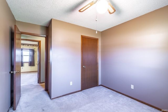 unfurnished bedroom featuring light carpet, a textured ceiling, and ceiling fan