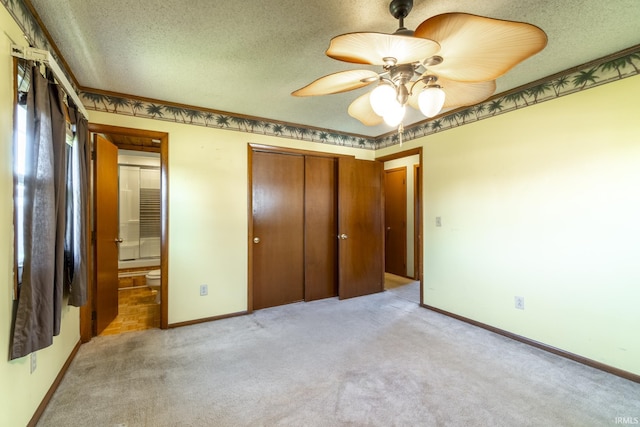 unfurnished bedroom featuring ceiling fan, a textured ceiling, a closet, and light carpet