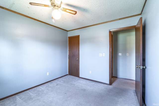 spare room featuring ceiling fan, a textured ceiling, carpet, and crown molding