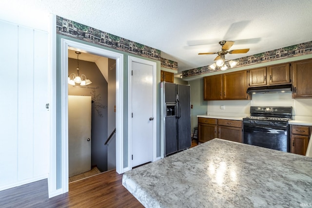 kitchen featuring black appliances, a textured ceiling, dark wood-type flooring, and hanging light fixtures