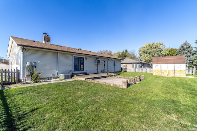 rear view of property featuring central AC unit, a patio area, a yard, and a storage unit