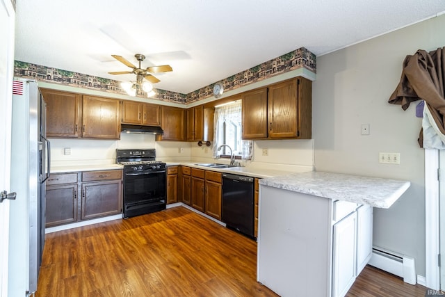 kitchen featuring black appliances, kitchen peninsula, a baseboard heating unit, and dark hardwood / wood-style floors