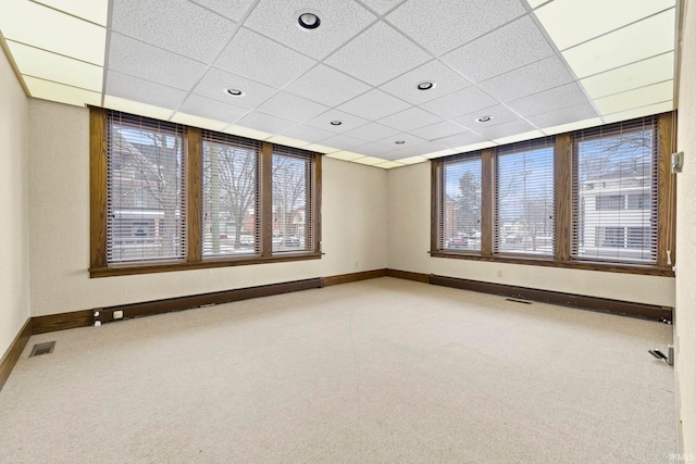 carpeted empty room with a baseboard heating unit and a paneled ceiling