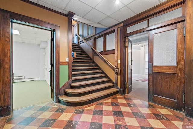 entryway featuring baseboard heating, a drop ceiling, and dark carpet