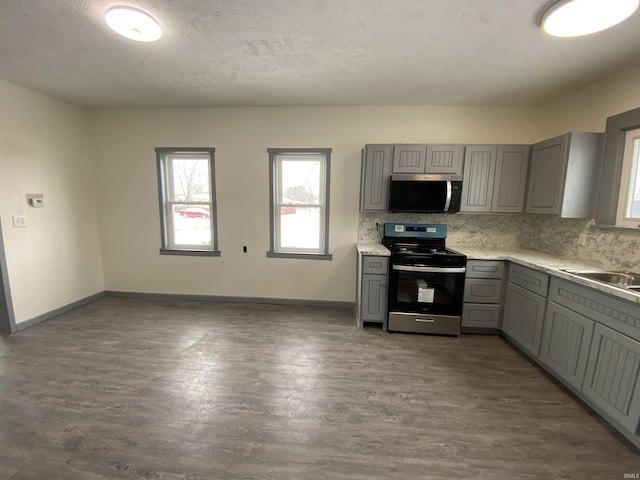 kitchen with sink, backsplash, dark hardwood / wood-style floors, range with electric stovetop, and gray cabinetry