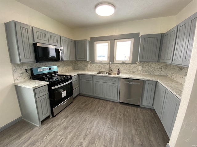 kitchen featuring sink, hardwood / wood-style floors, gray cabinetry, and stainless steel appliances