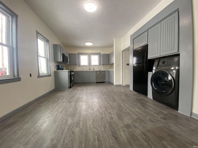 clothes washing area featuring dark wood-type flooring, sink, a healthy amount of sunlight, and washer / clothes dryer