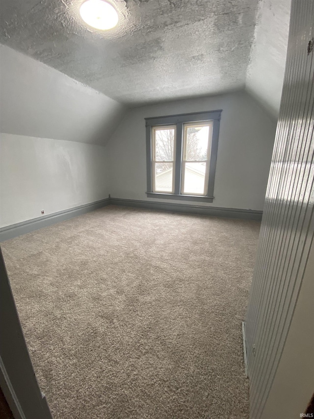 bonus room featuring a textured ceiling, vaulted ceiling, and carpet