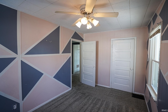 unfurnished bedroom featuring ceiling fan, a closet, and dark colored carpet