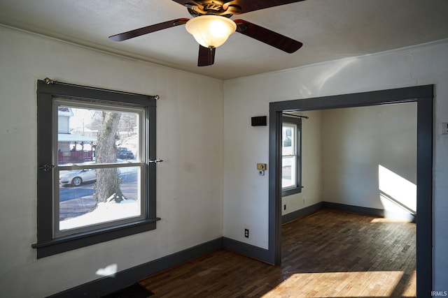 spare room featuring a healthy amount of sunlight, ornamental molding, and dark hardwood / wood-style floors