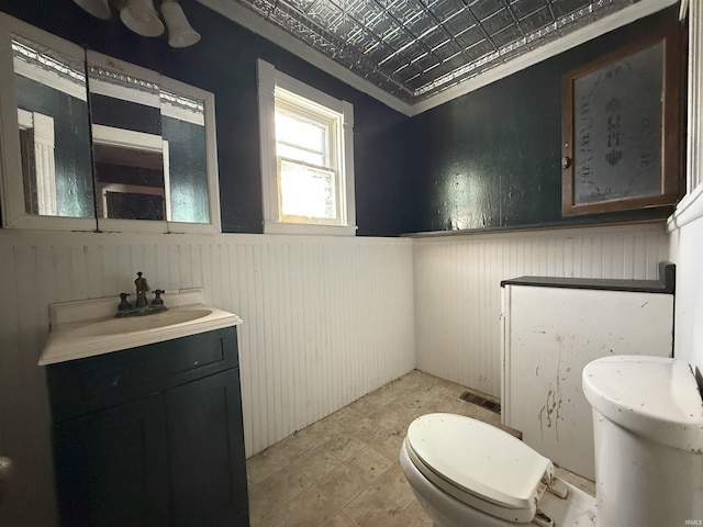 bathroom with vanity, toilet, ornamental molding, and wooden walls