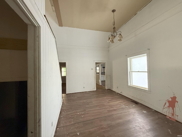 spare room with dark wood-type flooring, a notable chandelier, and vaulted ceiling